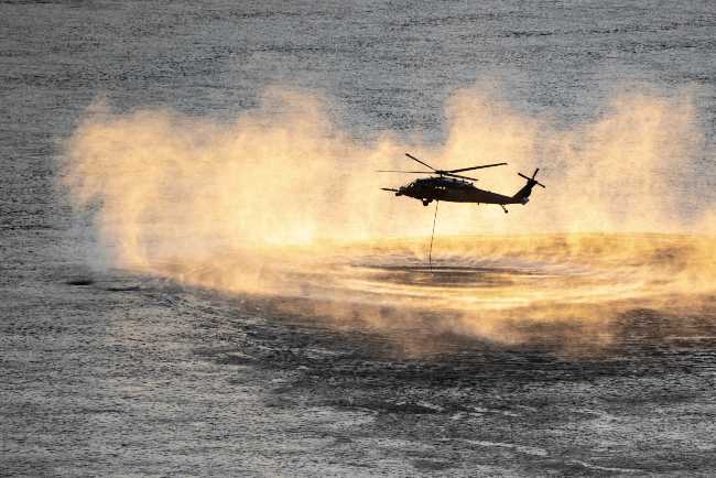 a helicopter above a lake performing a search and rescue operation