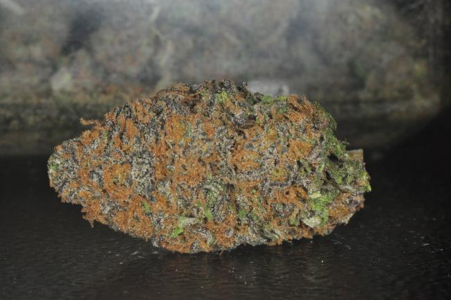 An orange and purple cannabis nugget sitting on a black surface